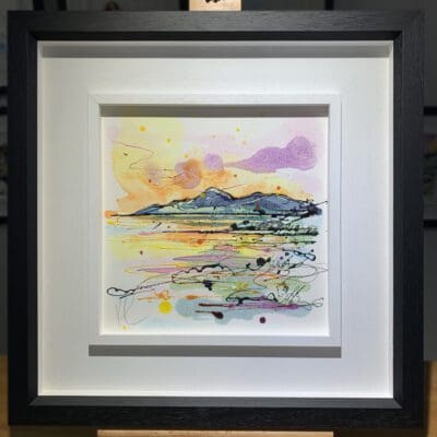 An original painting named The Mournes at Sunset by Kathryn Callaghan, featuring a view across Dundrum Bay to the Mourne Mountains in Northern Ireland. The painting is framed in a two part white and black frame.