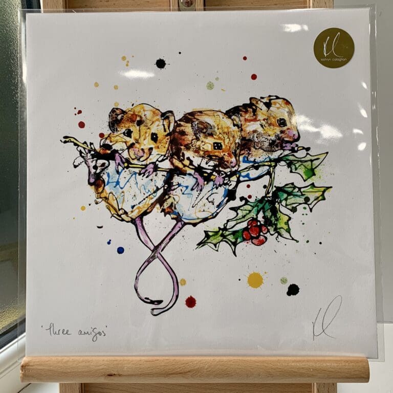 A print of Three Amigos by Kathryn Callaghan, which features three harvest mice clinging to a holly branch. The 30cm print is presented flat in a clear cello bag with a golden KC sticker in the top right.