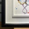 The bottom left corner of Three Amigos, an original painting by Kathryn Callaghan, which shows the two part white and black wooden frame and the artist's signature on the painting.