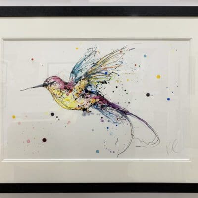 An original painting of a hummingbird in flight by Kathryn Callaghan, with an off white mount and a black frame.