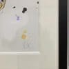 A close up image of the frame and artist's signature for No Holding Back, a painting of a running hare by Kathryn Callaghan.