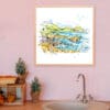 A 45cm print of Causeway Rocks by Kathryn Callaghan shown in a wooden frame in situ.q
