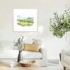 A 45x45cm print of Glens of Antrim by Kathryn Callaghan, shown in a beech wood frame in situ.